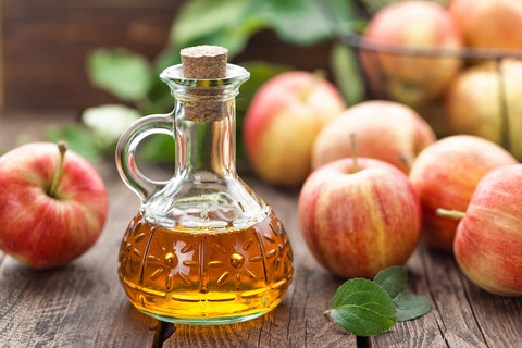 Eine Flasche mit Apfelessig und Äpfel