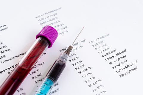Magnesiummangel beheben: Spritze und Ampulle mit Blut auf einem Bluttest-Befund
