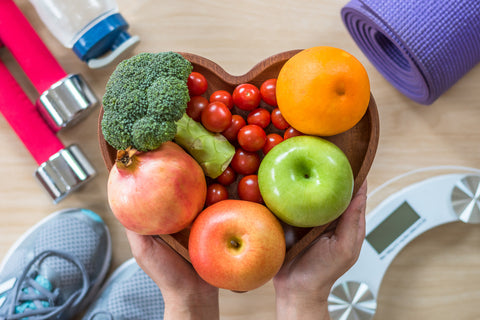 Schale mit Obst und Gemüse, Waage, Hanteln und Sportschuhe