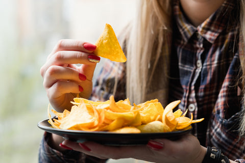 Eine Frau isst von einem Teller Nachos