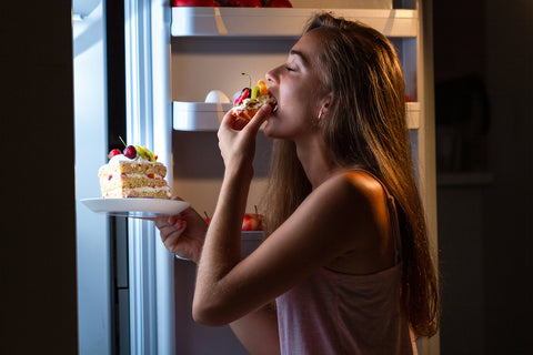 Frau isst nachts Kuchen