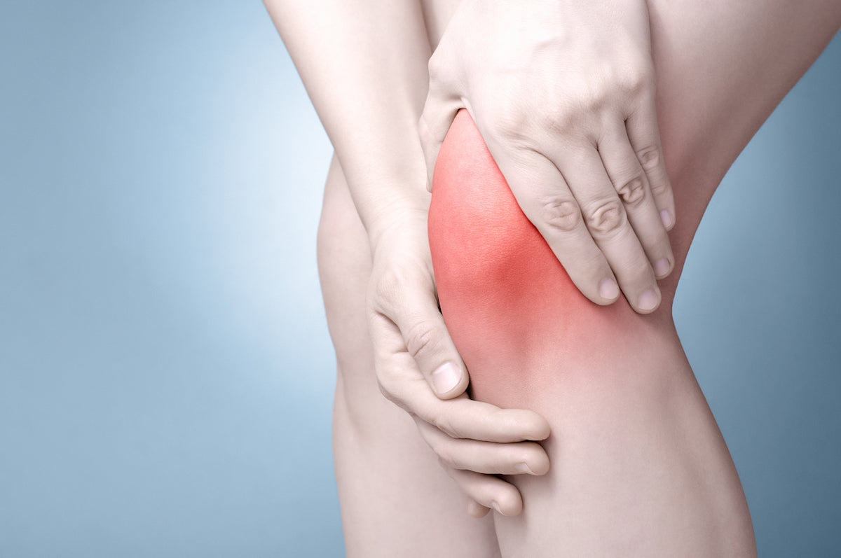 Person hält sich das Knie vor Schmerzen