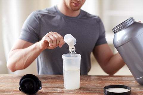Mann gibt Kreatinpulver in einen Shaker