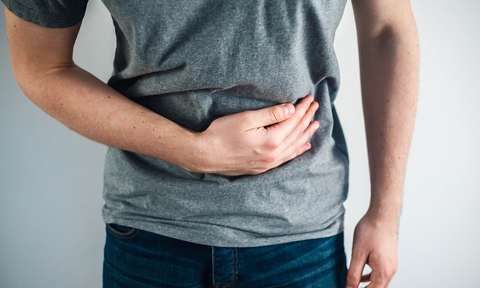 Verdauungsenzyme - Symptome bei Mangel an Verdauungsenzymen: Mann hält sich vor Schmerzen die Hand an den Bauch