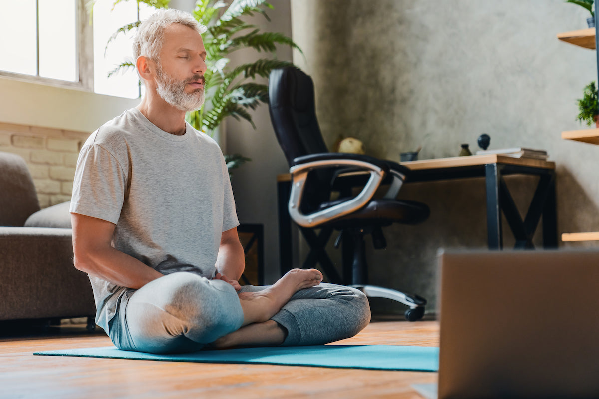 Mann sitzt in Meditationshaltung auf dem Boden