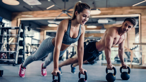 Eine Frau und ein Mann machen Kraftsport mit Kettlebells