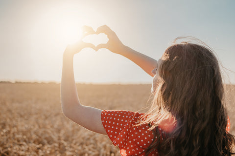 Nährstoffe in der Schwangerschaft: Frau macht mit ihren Händen ein Herz vor der Sonne