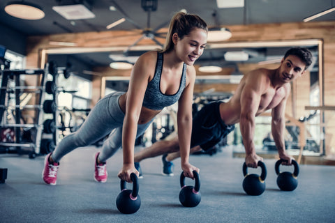 Eine Frau und ein Mann trainieren mit Kettlebells im Fitnessstudio
