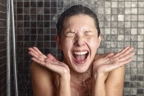 Eine Frau steht in der kalten Dusche