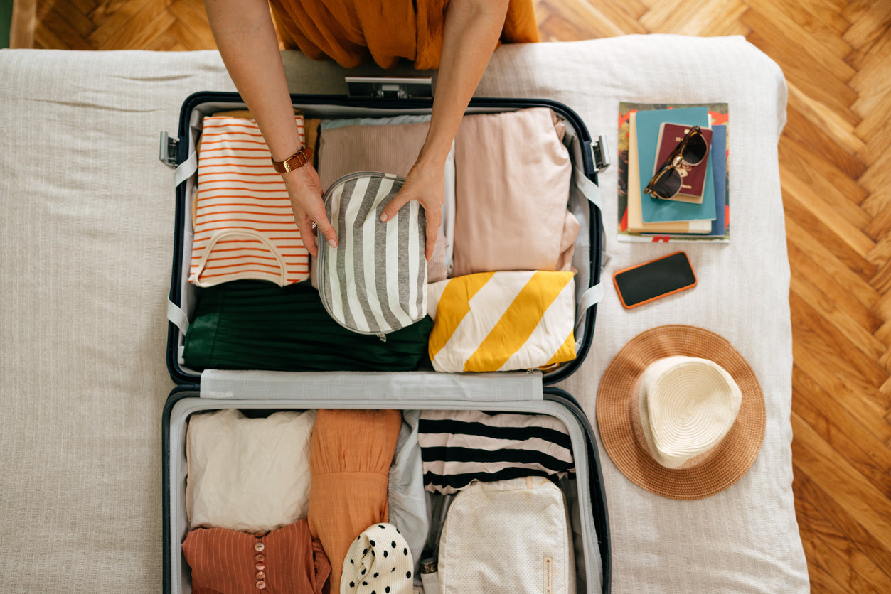Sommerurlaub-Essentials: Person packt einen Koffer