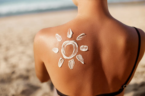 Eine Frau hat eine mit Sonnencreme gemalte Sonne auf der Schulter am Strand